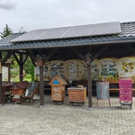 Ogród edukacyjny z tablicami prezentującymi rośliny miododajne i produkty pszczele.